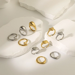 Polished stainless steel rings in heart and drop shapes on white textured stone