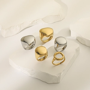 Detailed arrangement of high-polish minimalist gold and silver rings on white stone