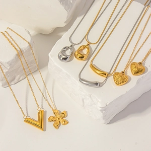Détail de colliers plaqués or 18K et argent avec pendentifs en V et cœur sur pierres