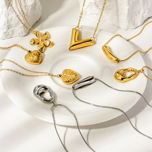 Pendentifs assortis or et argent en forme de cœur, fleur et V sur une assiette blanche