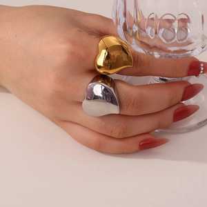 Close-up of chunky gold and silver heart-shaped rings with mirror-polished finish