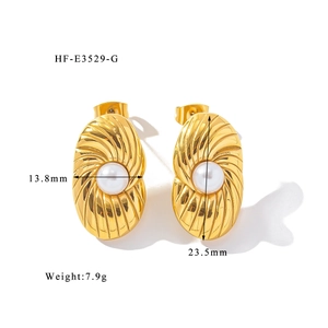 Dettaglio di orecchino placcato oro 18K con trama a spirale e perla bianca al centro