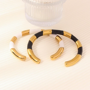 Bracciali aperti in acciaio al titanio con smalto bianco e nero e trama bambù dorata