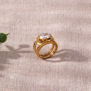 Modern 18K gold-plated double-band ring with a large oval zircon on a neutral background