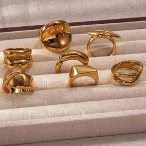 Macro di anelli geometrici placcati oro 18K esposti in un portagioie in tessuto beige