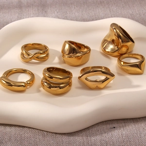 Set di 7 anelli spessi dorati minimalisti in forme geometriche su un vassoio espositivo