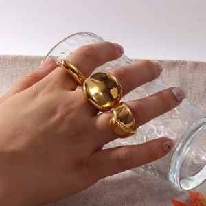Set di tre anelli minimalisti placcati in oro 18K indossati con mano e bicchiere