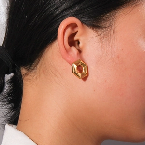 Boucles d'oreilles hexagonales géométriques dorées avec finition polie sur modèle
