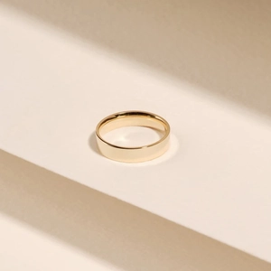 Polished 18k gold plated stainless steel minimalist flat band ring on beige steps