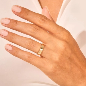 Close-up of minimalist flat gold plated titanium steel ring on model's finger