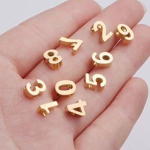 Golden stainless steel 0-9 number charms for DIY jewelry making shown on hand