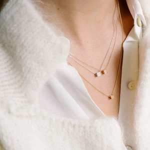 Close-up of triple-layered necklaces with gold, silver, and rose gold square letter charms