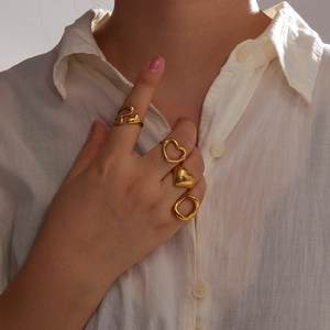 Gedetailleerd zicht op een vierdelige 18K vergulde hart en geometrische ringenset op model