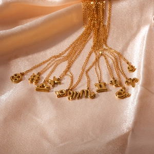 Polished 18K gold plated stainless steel zodiac necklaces on elegant champagne silk