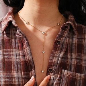 Detail of 18K gold Y-necklace with five heart pendants and small clear zircon stones
