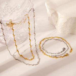 Collier à chaîne ondulée en plaqué or 18K et argent présenté sur un verre décoratif