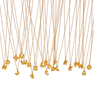 Detail view of gold bubble letter pendants in 18K plated stainless steel on thin chains