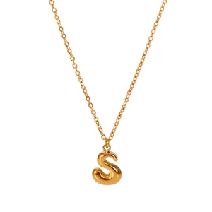 Macro detail of high-polish 18K gold letter S bubble pendant on a slim cross chain