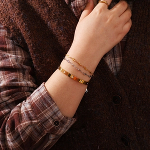 Détail de bracelet jonc doré avec étoile gravée et fines chaînes ondulées superposées