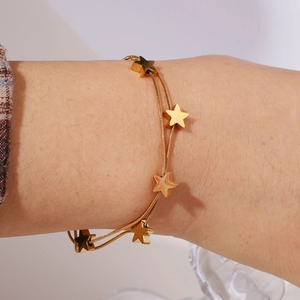 Close-up of a double-layered gold star bracelet with delicate snake chains on a wrist