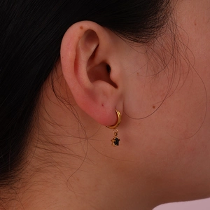 18K gold plated hoop earrings featuring a black star-shaped glass pendant on model
