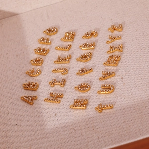 18K gold plated A-Z initial pendants set with sparkling zircons on burlap background