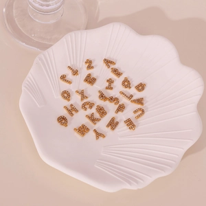 26 gold-plated 18K letter charms with sparkling cubic zirconia on a shell plate