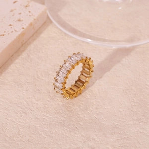 Macro detail of 18k gold plated eternity ring with rectangular zircon stones on stone background