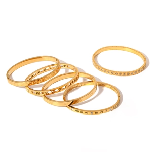 Stack of gold plated stainless steel bangles featuring Roman numerals and leaf patterns