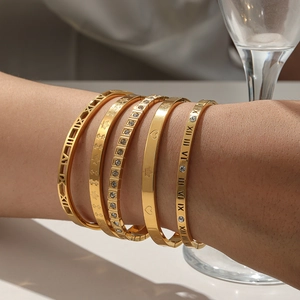 Five-piece gold stainless steel bangle set with Roman numerals and maple leaf charms