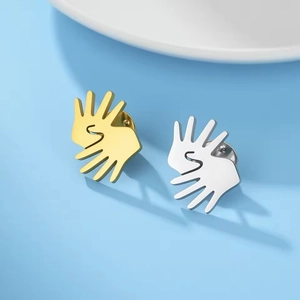 Macro view of gold and silver sign language hand pins on light blue background