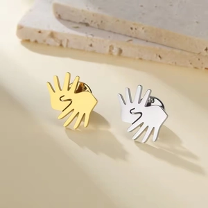 Detailed close-up of gold and silver sign language hand gesture brooches with polished finish