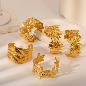 Gold-plated floral open bangles featuring sunflower and leaf designs on stone pedestal