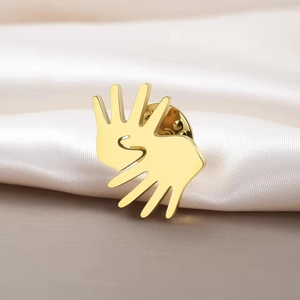 Golden sign language gesture brooch in mirror polished stainless steel on white silk