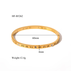 Macro detail of gold plated bangle showing Roman numeral engraving and cubic zirconia stones
