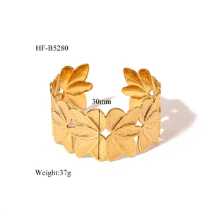 Macro view of wide 18K gold-plated leaf-shaped open bangle with brushed metal texture