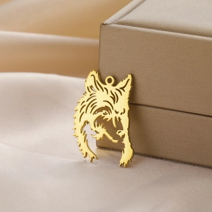 Detail of a gold wolf head pendant with cut-out design on a warm satin background