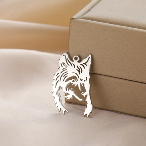 Detailed view of hollow vintage wolf head pendant on luxury gold satin fabric background
