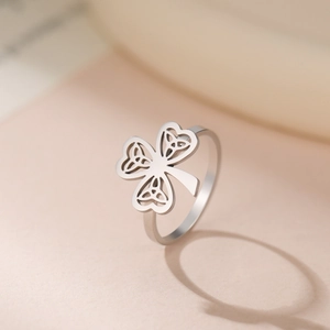Silberner Kleeblatt-Ring aus Edelstahl mit keltischem Knotenmuster auf warmem Hintergrund