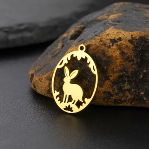 Detailed macro of golden hollow rabbit pendant on textured stone background for DIY