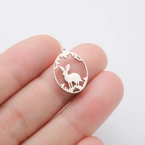 Detailed macro view of a rabbit in flowers stainless steel pendant held by hand