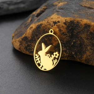 Macro detail of gold oval rabbit and flower pendant on natural stone base