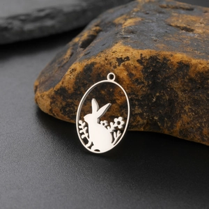 Close-up of oval stainless steel bunny rabbit charm with floral silhouette cutout