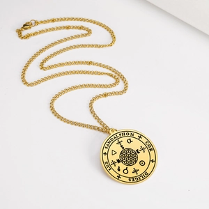 Vue détaillée du pendentif en acier doré avec des gravures mystiques concentriques