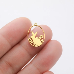 Detail of bunny and floral hollow pendant in gold-plated steel held for size scale