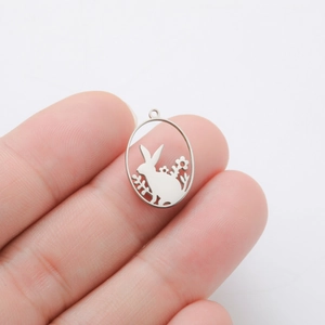 Detailed macro view of an oval stainless steel bunny and flowers pendant for DIY jewelry