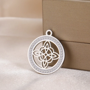 Polished stainless steel Celtic knot pendant with sparkling crystals on silk background
