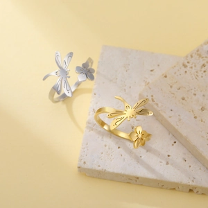 Detail of dragonfly and flower motifs on gold and silver stainless steel rings