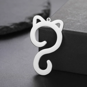 Macro shot of silver polished stainless steel cat-shaped pendant on dark stone surface