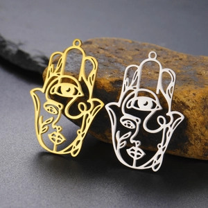 Detailed close-up of gold and silver Hamsa hand pendants with abstract face engraving